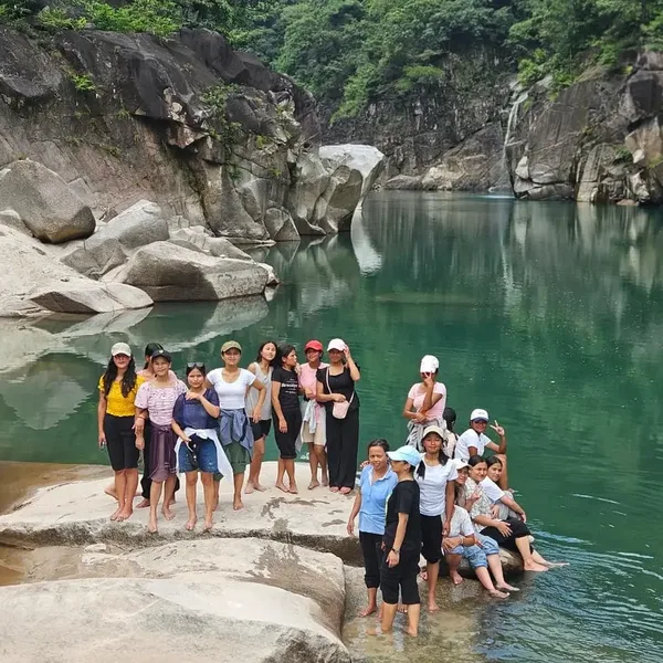 Students on a trip standing on rocks beside a river